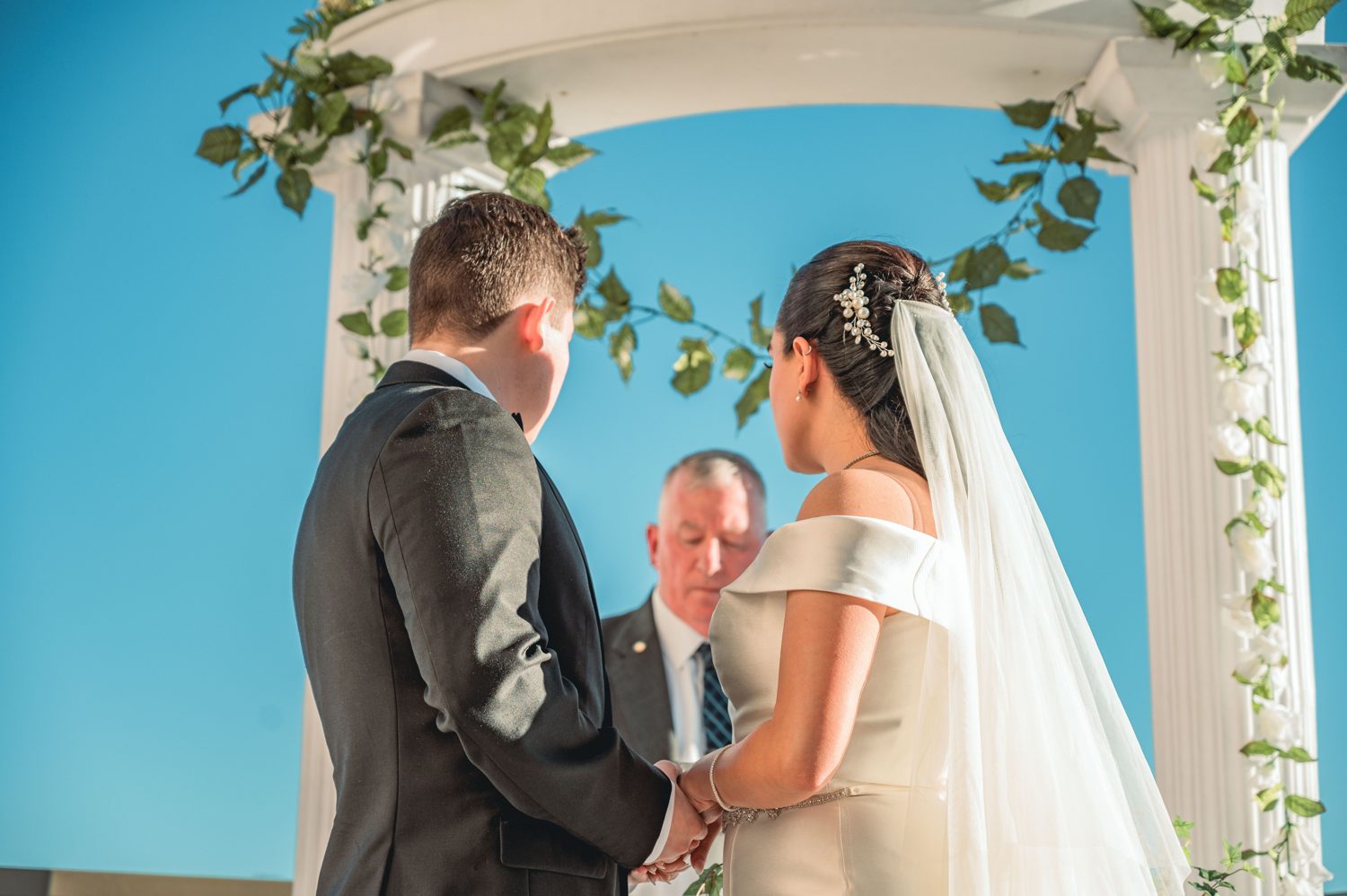 Als Favorit markiertes Hochzeitsfoto: Brautpaar Hand in Hand bei der Trauung